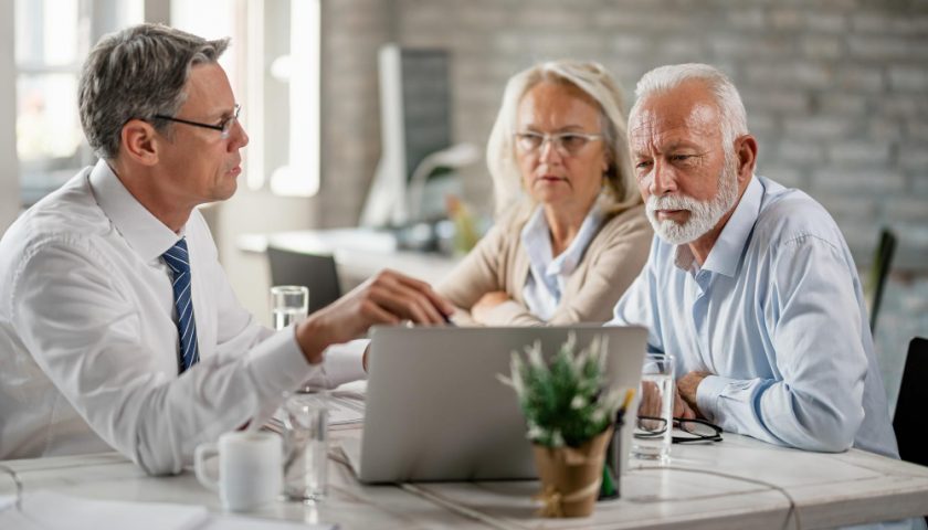 un couple de senior qui discute avec un homme en costume