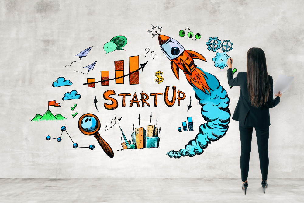 une femme fait un dessin représentant une start up sur un mur