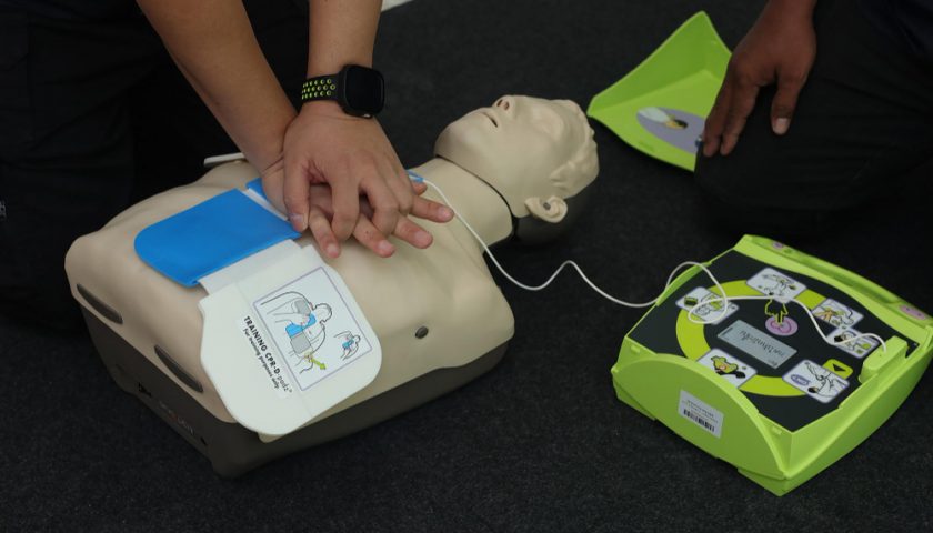 une personne faisant un massage sur un mannequin à l'aide d'un défibrillateur