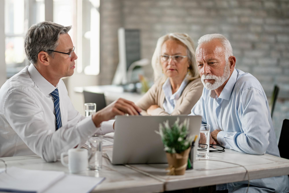 un couple de senior qui discute avec un homme en costume