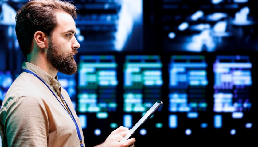 un homme avec une tablette devant des serveurs